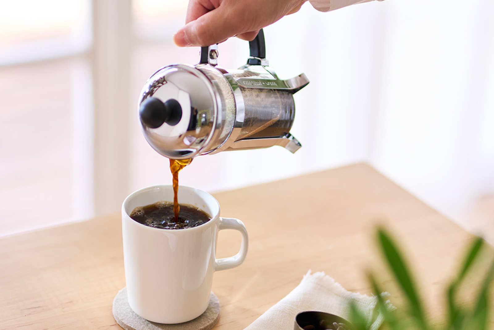 コーヒープレスでいれたコーヒーをマグカップに注いでいる様子
