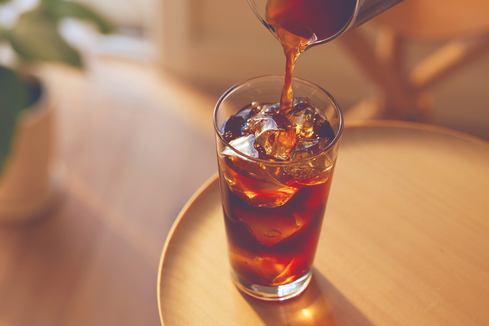 グラスいっぱいに入れた氷にコールドブリューコーヒーを注ぐ様子