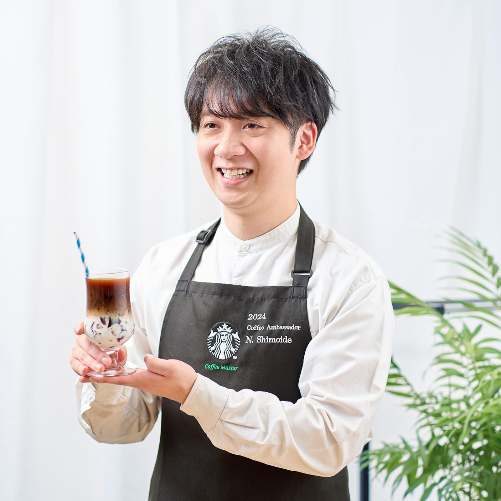 コーヒーアンバサダーの下出さんがスターバックス® アイスコーヒー ブレンドをアレンジしたキャラメルゼリーマキアートを片手にインタビューを受けている様子